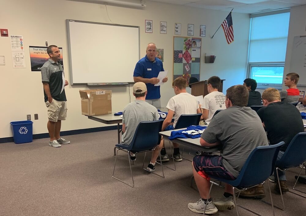 Coach and Fund U Coach talk to the football team about fundraising