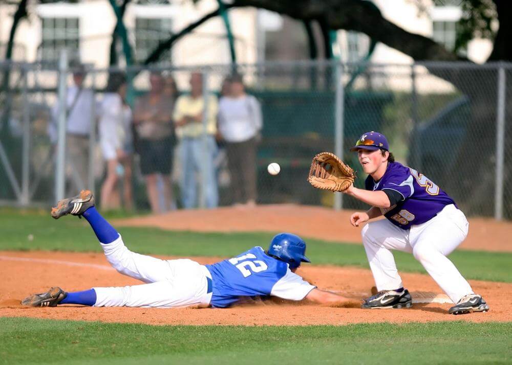 a baseball player slides into home plate as the catcher catches the baseball