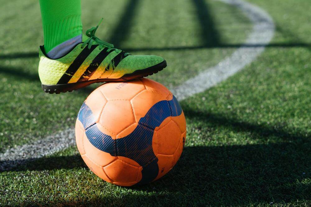 yellow cleat stands on orange soccer ball