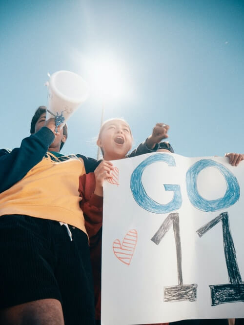 a girl holding a go 11 banner and a boy holding a microphone